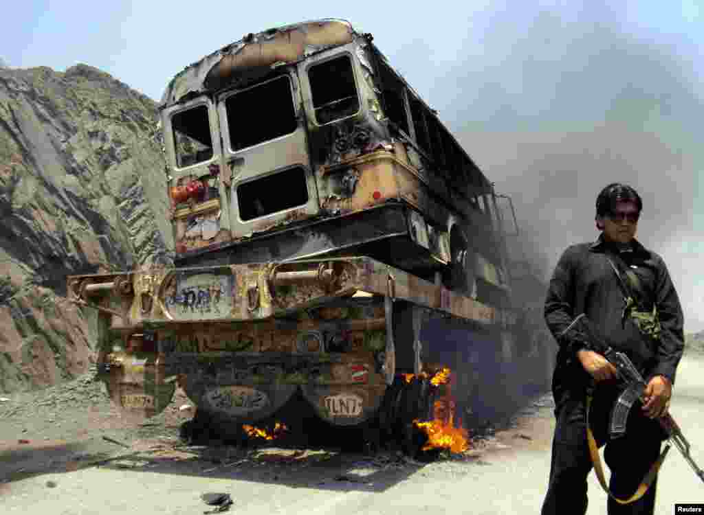 A tribal policeman stands guard near a burning NATO supply convoy in the Khyber tribal region of Pakistan. Militants armed with rocket launchers and sophisticated weapons attacked three NATO supply trucks close to the Pakistan-Afghan border, killing six. (Reuters/Shahid Shinwari)