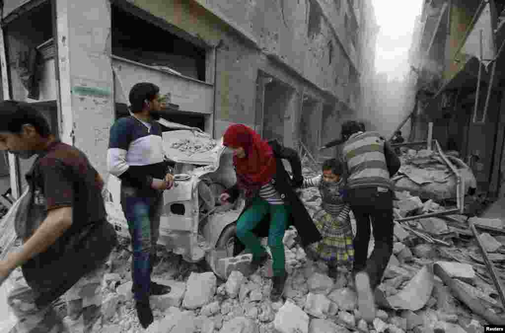 A woman holds the hand of a girl as they rush away from a site hit by what activists said was an air strike by government forces in Aleppo's Al-Fardous district. (Reuters/Rami Zayat)