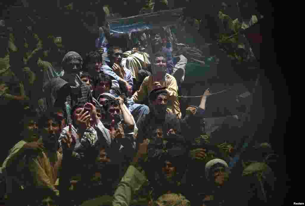 Supporters of Afghan presidential candidate Abdullah Abdullah are seen through a broken window during an election campaign in Qala-e Naw, capital of Badghis Province, on June 2. (Reuters/Mohammad Ismail)