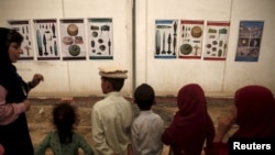 Afghan refugee children returning from Pakistan listen to an aid worker speak about mines.