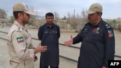 FILE: A Pakistani border security official (R) and an Iranian border official meet at Zero Point in the Pakistan-Iran border town of Taftan in October 2018.