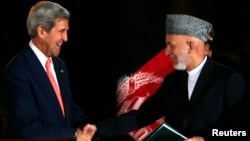 Afghan President Hamid Karzai (right) shakes hands with U.S. Secretary of State John Kerry after a news conference in Kabul on October 12.