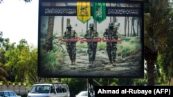 IRAQ -- A propaganda billboard for the pro-Iran Hizballah Brigades militia is seen hanging over Palestine Street in the centre of the Iraqi capital Baghdad, June 20, 2018