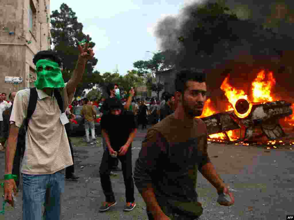 Smoke billows from a car that was set on fire by angry protesters.