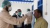 FILE: A doctor checks the temperature of a man returning from Iran at a quarantine zone to test for the COVID-19 coronavirus in the Pakistan-Iran border town of Taftan in February.