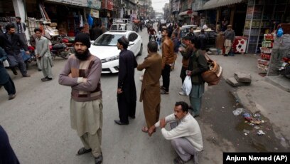 People stand outside their shops after a severe earthquake is felt in Rawalpindi, Pakistan, on January 31.