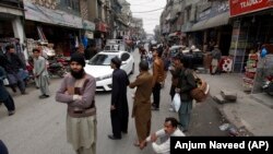 FILE: People stand outside their shops after a severe earthquake is felt in Islamabad in January.