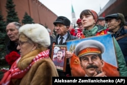 A woman holds a portrait of Josef Stalin near the Kremlin as people gather in December 2017 to mark the anniversary of the dictator's birth.