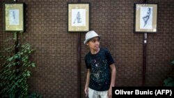 FILE: 10-year-old Farhad Nouri from Afghanistan poses in front of his drawings during his first exhibition in Belgrade in August.
