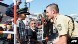 A German police officer and a migrant boy share a lighter moment after the latter's arrival at the main train station in Munich. Germany is expected to receive hundreds of thousands of asylum-seekers this year. 