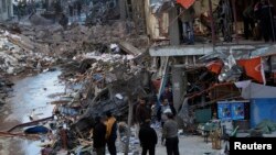 People inspect the damage after an explosion near a security building in Egypt's Nile Delta city of Mansura, in Dakahlyia province, about 120 kilometers northeast of Cairo, on December 24, killing or injuring scores of people.