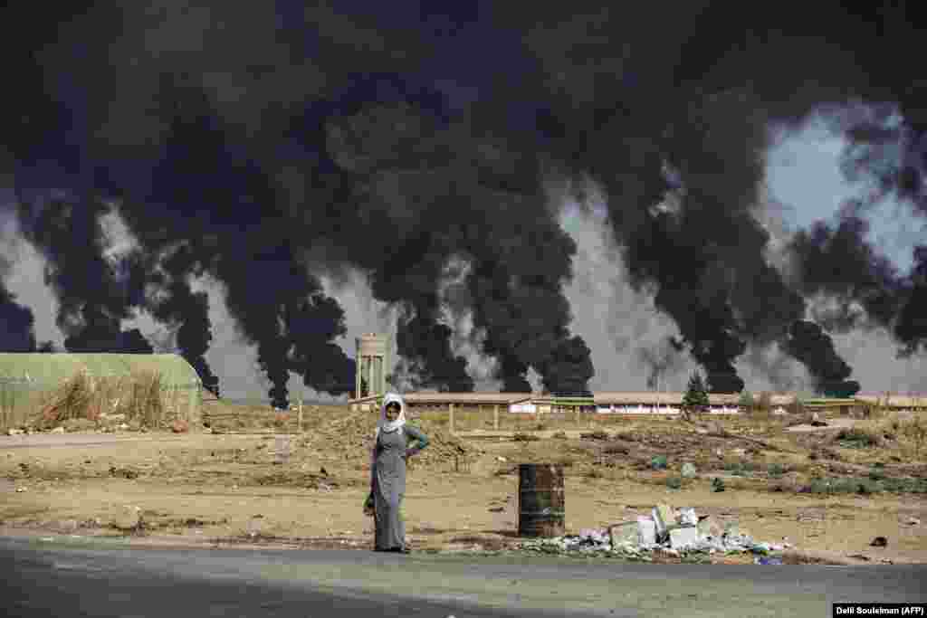 A woman stands along the side of a road near the Syrian Kurdish town of Ras Al-Ayn along the Turkish border. (AFP/Delil Souleiman) 