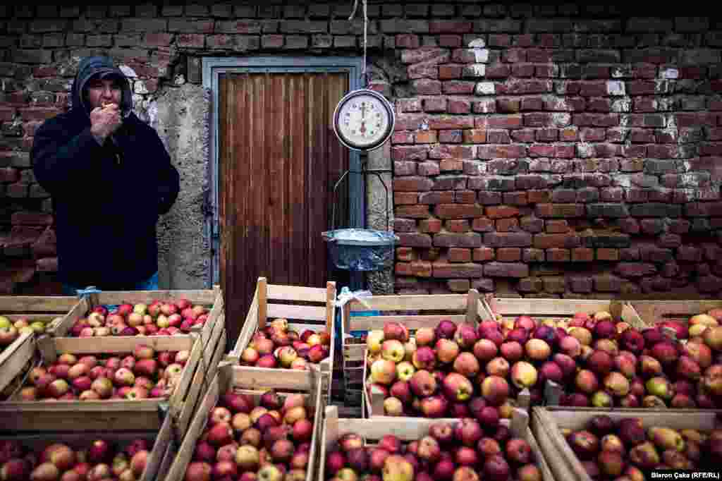 A fruit seller takes a chomp out of his wares at a market in Vushtrri. RFE/RL&#39;s Balkan Service asked Kosovar locals to take a picture &quot;that represents your reality that day.&quot; (Photo by Bleron Çaka)