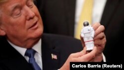 U.S. President Donald Trump holds an astronaut toy as he participates in a signing ceremony for the Space Policy Directive at the White House on December 11, 2017.