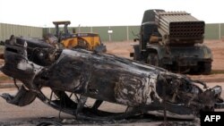 Destroyed vehicles litter the street following fighting in the Libyan town of Bani Walid