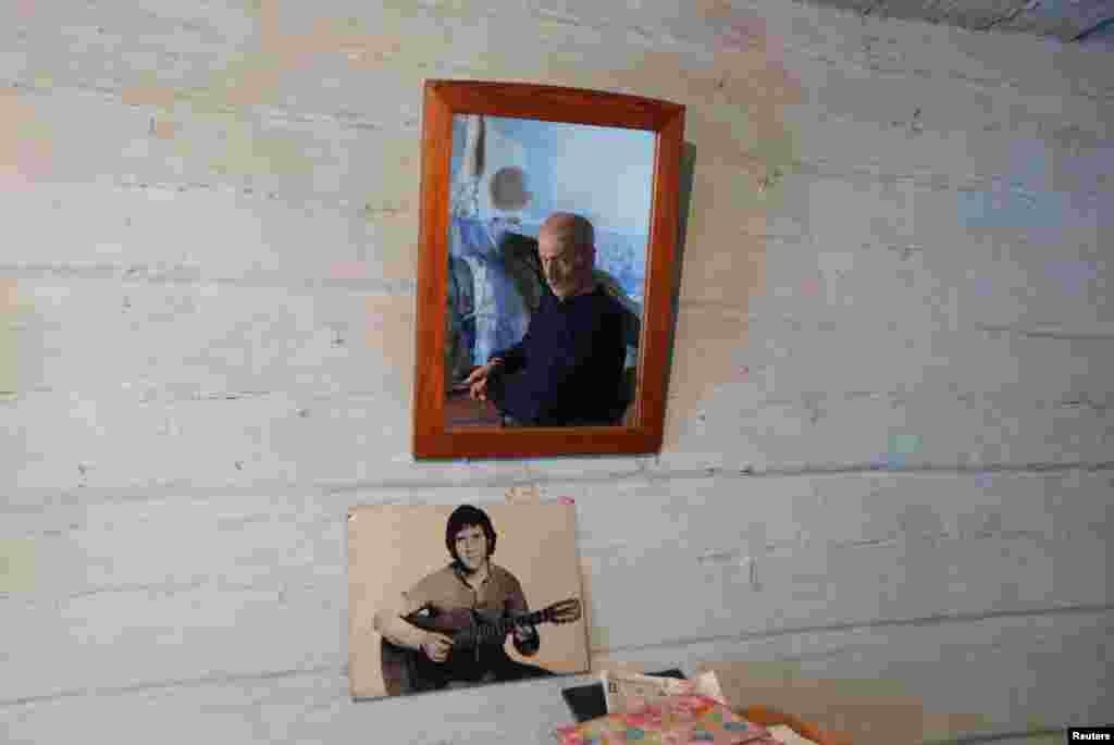 Mikhail Baburin, 66, is reflected in a mirror next to a portrait of Soviet singer, poet, and actor Vladimir Vysotsky at his house in the remote Siberian village of Mikhailovka. Baburin, a former Navy man, barge worker, and employee of a military plant in Krasnoyarsk, is the last inhabitant of Mikhailovka, which was founded in the 19th century by migrants from Russia's Mordovia region. (Reuters/Ilya Naymushin)