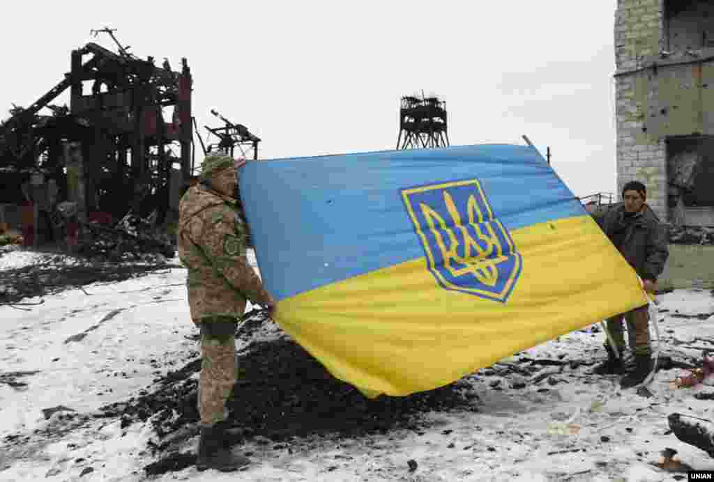 Військові з прапором України біля обваленого внаслідок нічного обстрілу копера шахти Бутівка (неподалік Авдіївки), 27 лютого 2017 року БІЛЬШЕ ПРО ЦЕ