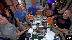 U.S. astronauts and Russian cosmonauts make pizza on the International Space Station.