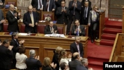 Prime Minister Antonis Samaras (blue tie) applauds with lawmakers after a vote at the parliament in Athens, on November 8.
