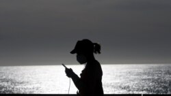 Žena s zaštitnom maskom šeta plažom u Barceloni, 2. svibnja