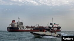 Eýranyň Rewolýusiýa sakçylarynyň gaýygy Hormuz bogazynda Britaniýanyň "Stena Impero" gämisiniň gapdalyndan geçip barýar. Arhiw suraty.