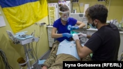 Валерия Алексеенко вместе с ассистентом лечит зубы бойцу в передвижном стоматологическом кабинете. Поселок Широкино, июль 2016