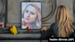 A woman places flowers next to a portrait of slain TV reporter Viktoria Marinova during a vigil at the Liberty Monument in Ruse on October 8. 