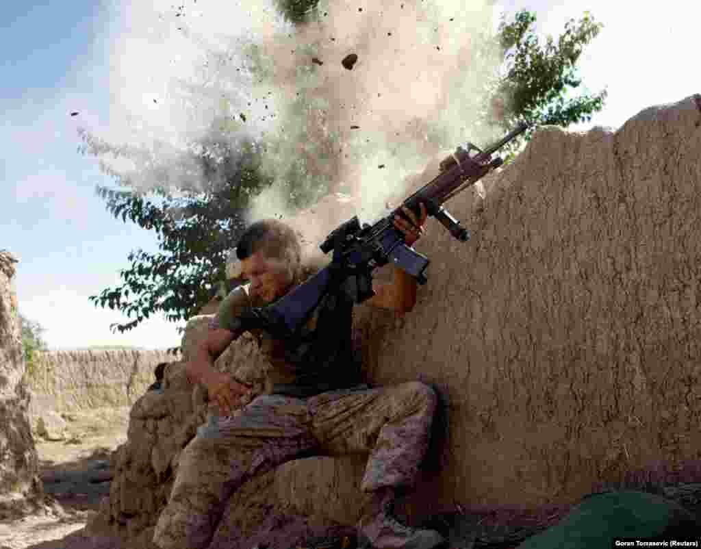 A U.S. Marine is knocked from his position by a Taliban bullet in Afghanistan. Tomasevic wrote that the wall seemed to &quot;explode from an incoming round and [he] was down. I dropped my cameras and jumped toward him. I felt his head and neck expecting to find blood, but there was none. He was breathing, but unconscious....&nbsp;It was his lucky day. He hadn&#39;t been hit or seriously hurt.&quot;