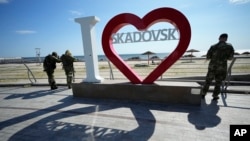 Russian soldiers stand by the waterfront in the occupied Ukrainian city of Skadovsk, Kherson region. Meanwhile, the people of the town "live in fear," one resident told RFE/RL. 