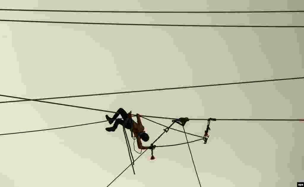 An employee of a private contractor is silhouetted against the sky as he works on power lines in Mumbai, India, on December 29. (epa/Divyakant Solanki)