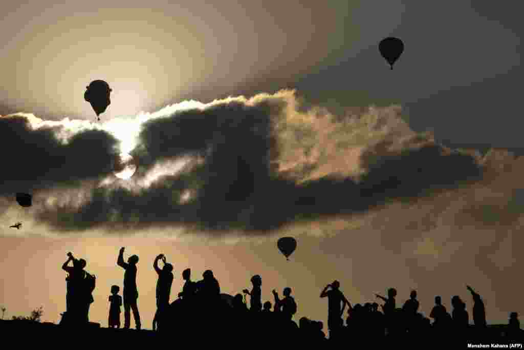 Ysraýyllylar Gilboa gyzgyn howa şarlary festiwalynda howa uçurylan gyzgyn şarlary synlaýarlar we surata düşürýärler. Kibbutz Ein Harod, demirgazyk Ysraýyl, Jezreel deresi. (AFP/Menahem Kahana)