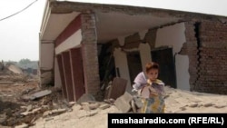 د مومندو يو ماشوم د خپل ويجاړ شوي ښوونځي سره ولاړ دی