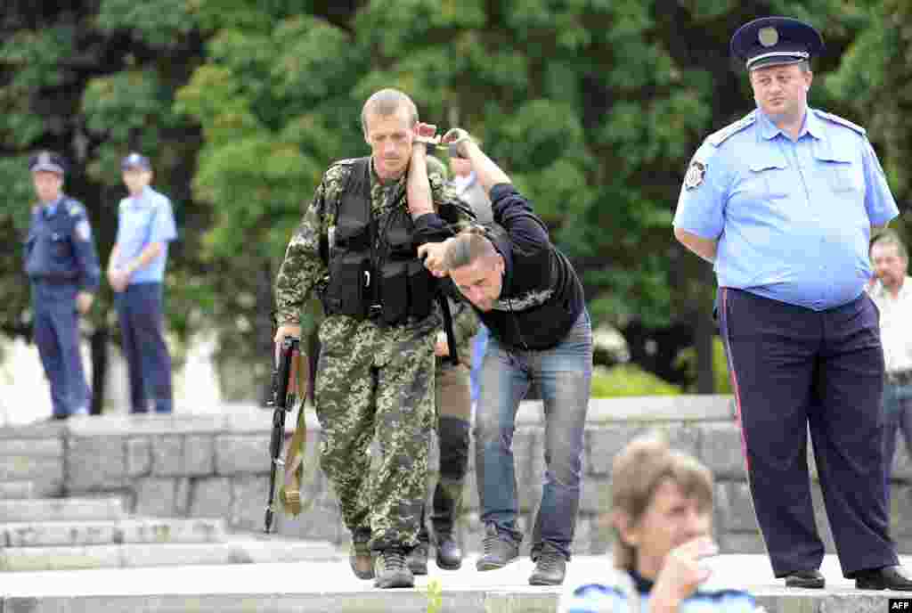 Проросійський бойовик затримує чоловіка, підозрюваного у шпигунстві для України, під час церемонії принесення присяги на вірність так званій &laquo;ДНР&raquo;, Донецьк, 21 червня 2014 року
