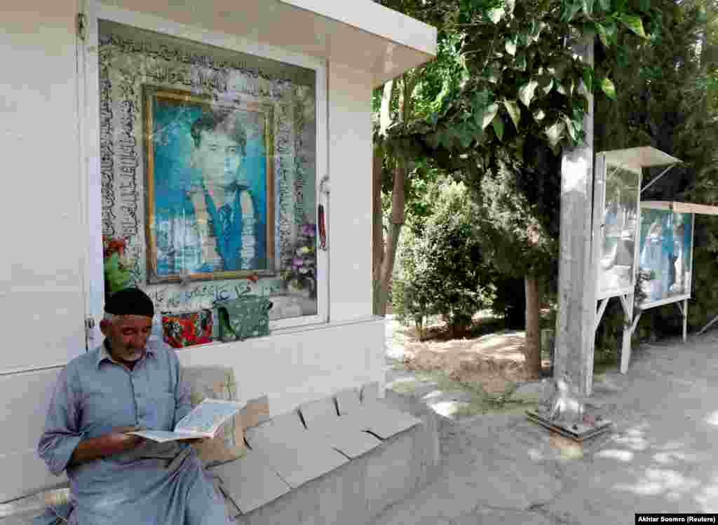 A Hazara man reads the Koran along a passageway with photos of deceased victims who lost their lives during target killings and bomb attacks, at the graveyard called Shuhda Qabristan (martyred graveyard) in Mariabad, Quetta, Pakistan, June 13.