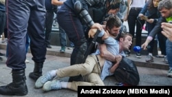 A man identified as Georgy Oganezov is forcibly detained by Russian riot police in Moscow on August 3 as Timur Olevskiy, an anchorman for Current Time, interviews him.