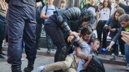 RUSSIA -- Timur Olevskiy, a TV anchor for Current Time TV, conducts an interview with a man as he is being detained by police at a rally to demand free municipal elections in Moscow, August 3, 2019