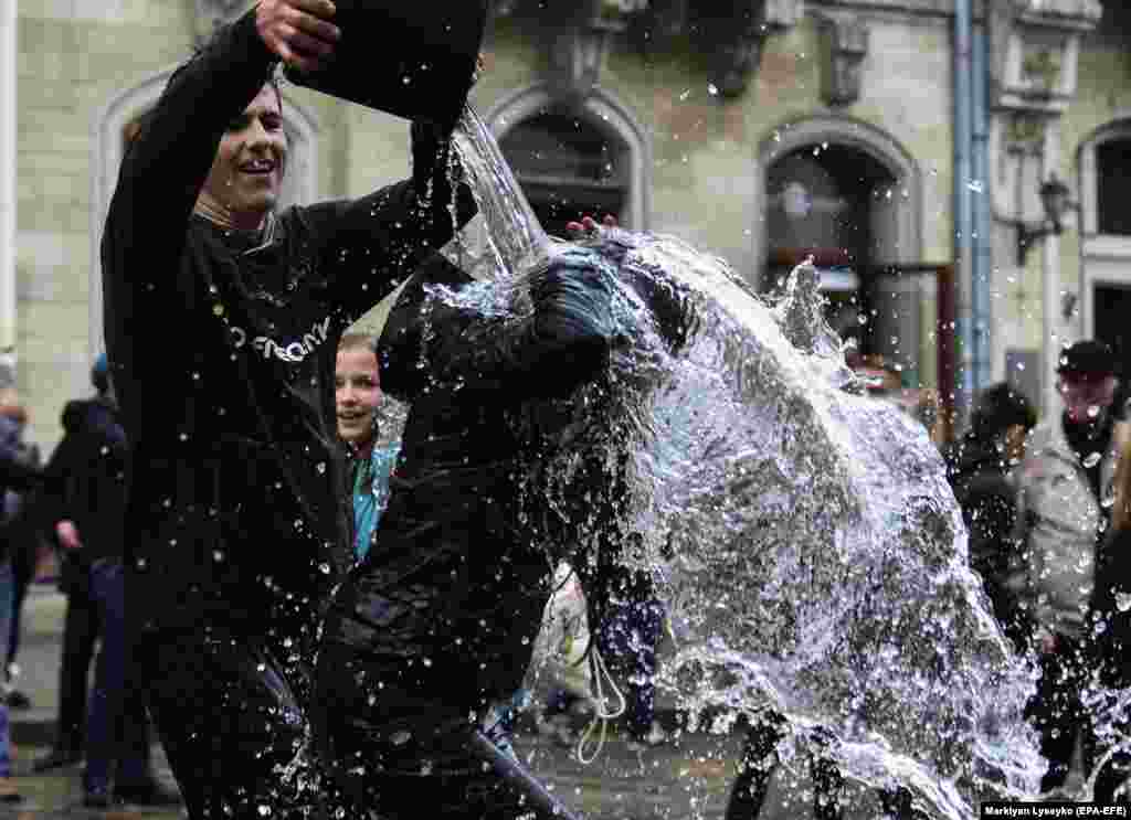 Ukrainians pour water on each other as part of Easter celebrations on a street in downtown Lviv on April 29. (epa-EFE/Markiian Lyseiko)