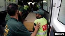 Hospital staff and rescue workers move the body of one of the 10 foreign tourists killed by gunmen near the Nanga Parbat peak in northern Pakistan. 