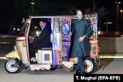 Prince William steps out of a brightly decorated "tuk-tuk" on his arrival to a gathering in Islamabad, the Pakistani capital.