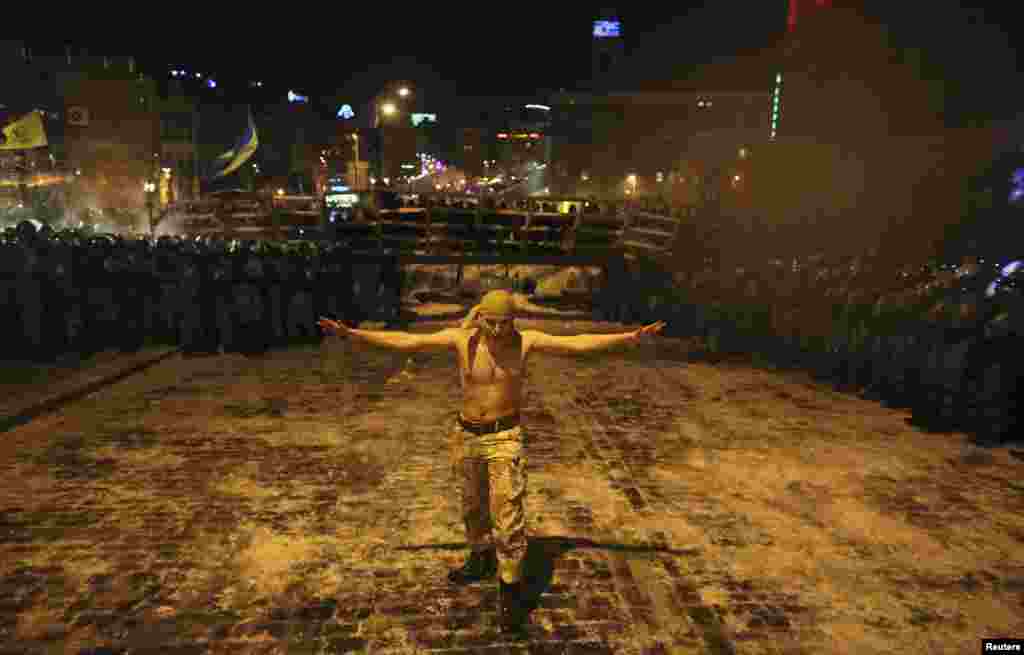 A Ukrainian antigovernment protester walks between a riot police line in Kyiv on December 11. (Reuters/Maksim Zveyev)