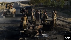 Afghan security forces investigate a site where vehicles were burned the previous night amid ongoing fighting against Taliban militants near the airport in Kunduz on October 1.