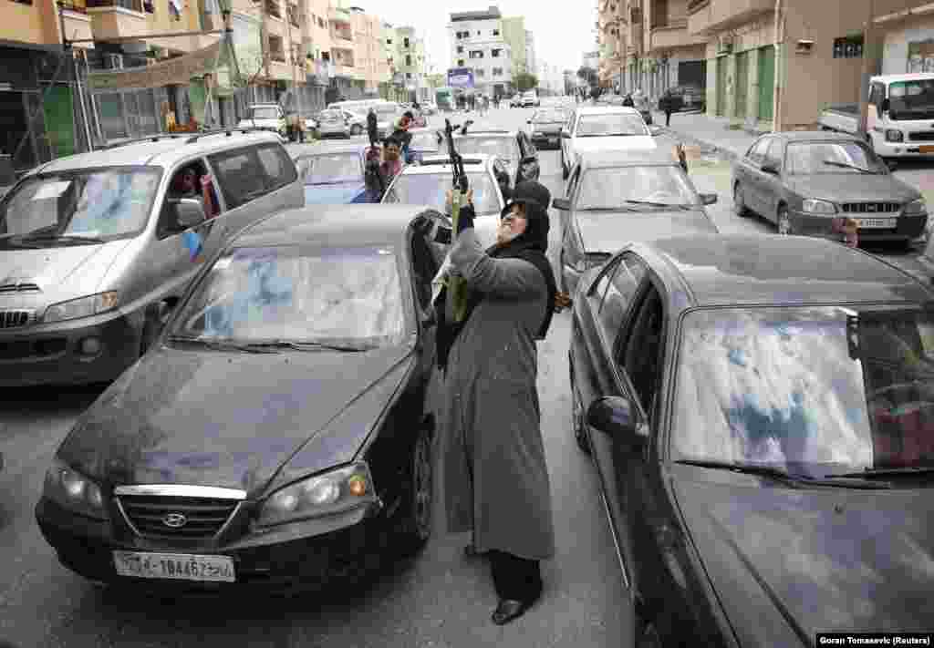 A woman shoots an AK-47 rifle as she celebrates news of the withdrawal of Libyan leader Qaddafi&#39;s forces from Benghazi on March 19, 2011.