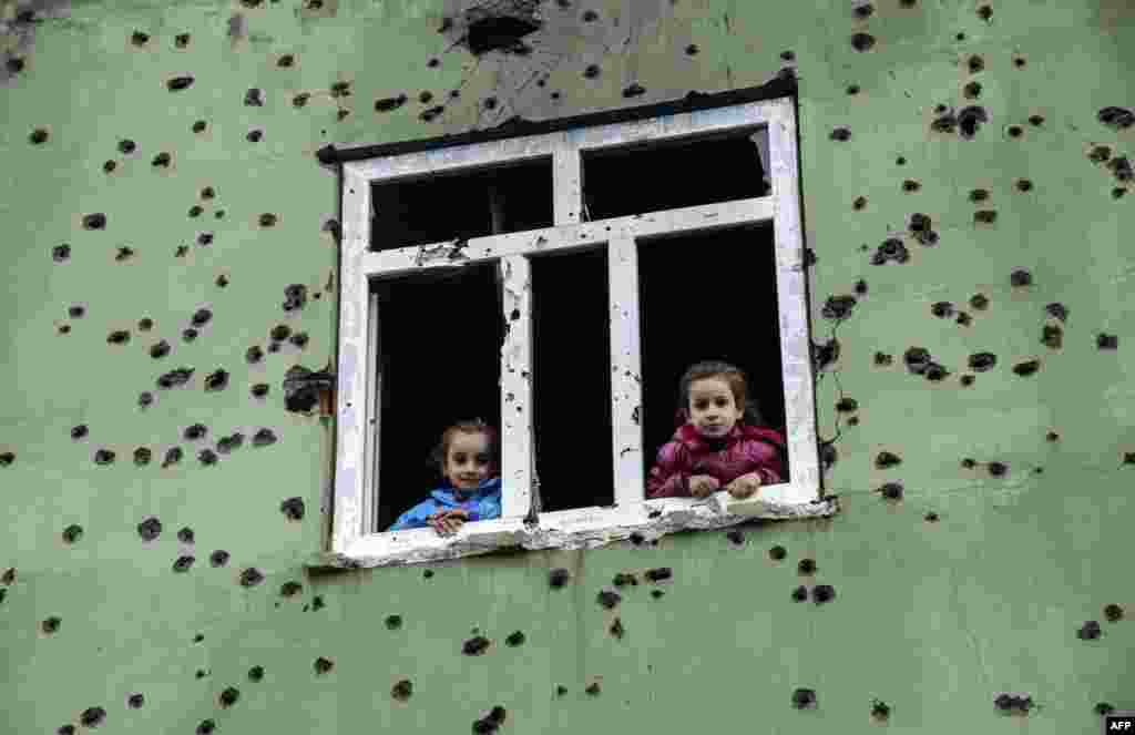 Children look out from a window of a bullet-scarred house in the Kurdish town of Silopi, in southeastern Turkey, near the border with Iraq. (AFP/Ilyas Akengin)