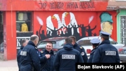 Police officers stand by the graffiti that shows a Serbian coat of arms and silhouettes of people, reading: "...because there's no turning back" in the northern Serb-dominated part of the town of Mitrovica on November 23.