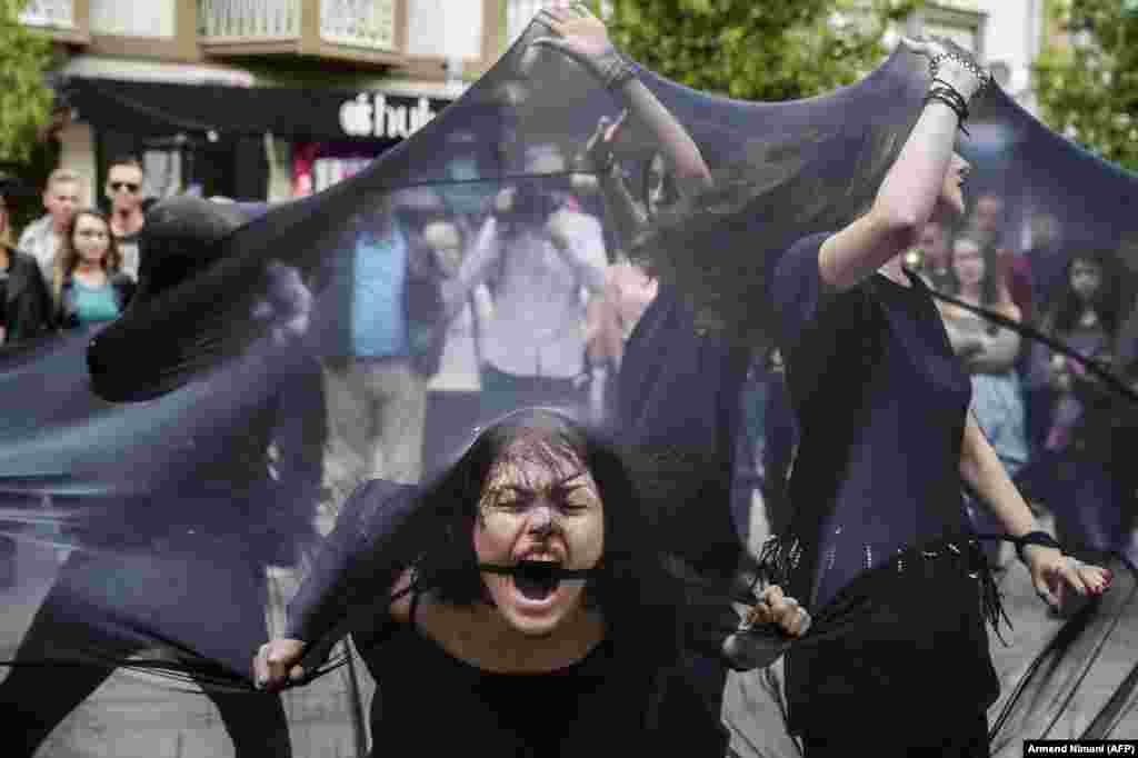 Women perform under black fabric during a street performance in Pristina, Kosovo, against sexual harassment. (AFP/Armend Nimani)