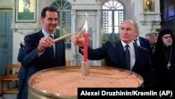 Президент России Владимир Путин (справа) и президент Сирии Башар Асад зажигают свечи во время рождественского посещения православного собора в Дамаске. Сирия, 7 января 2020 года.