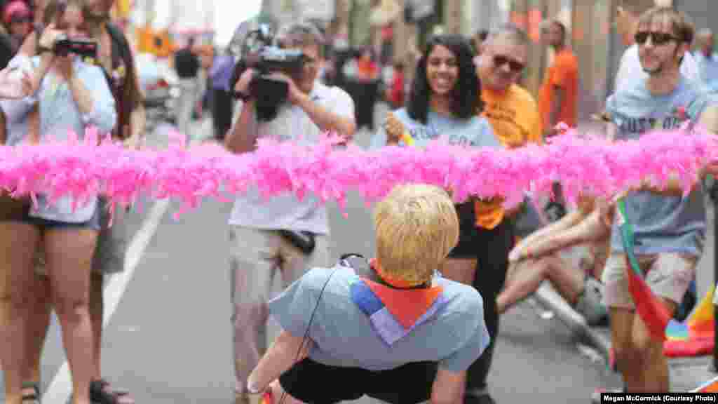 One of the participants does the limbo beneath a pink boa.