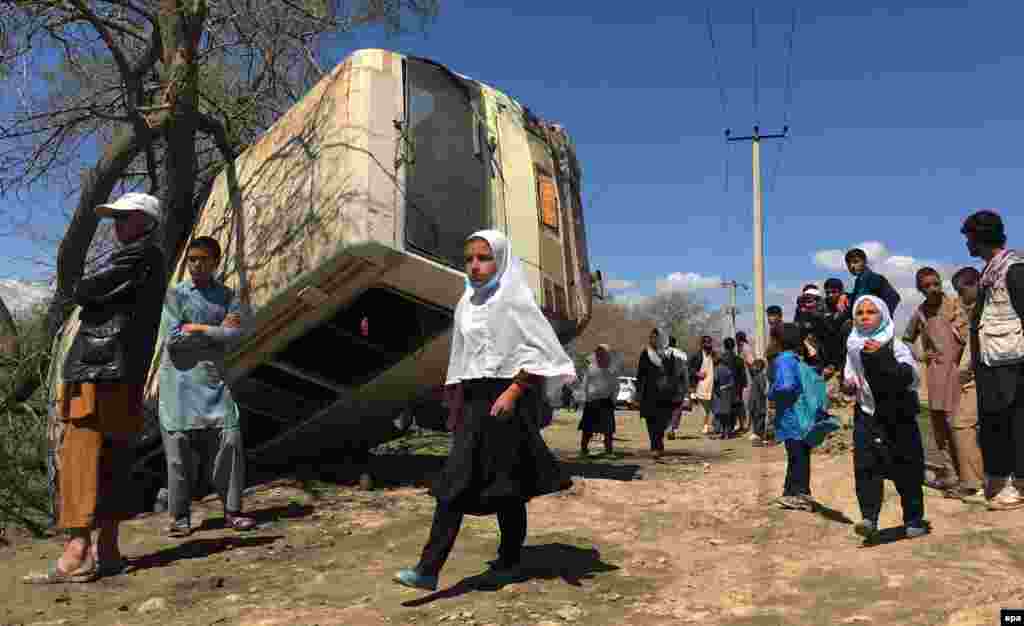 Schoolchildren pass by a bus that was transporting Education Ministry officials to work when it was hit by a roadside bomb on the outskirts of Kabul, Afghanistan, on April 11. (epa/Jawad Jalali)