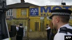 Police officers stand on duty in Barking, east London, following a dawn raid on a property as their investigations continue into a deadly attack in the center of the city on June 3 that left 7 people . 