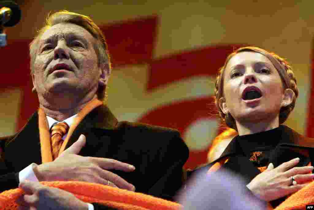 Orange Revolution leaders Viktor Yushchenko (left) and Yulia Tymoshenko sing the national anthem with supporters during the Orange Revolution in December 2004.